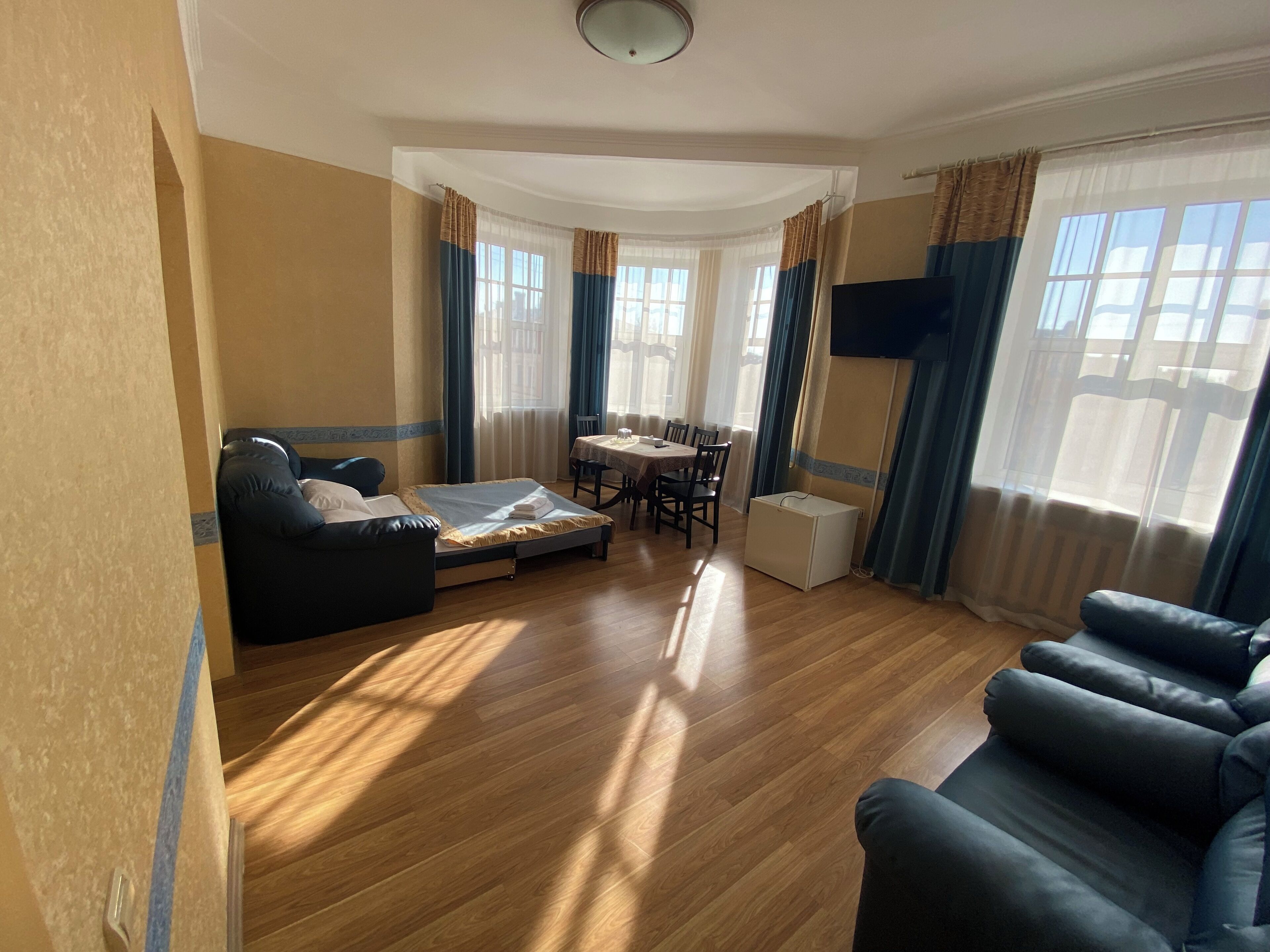 A room with a sofa, a small table, a TV, and a window with curtains.