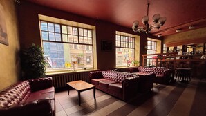 A cozy lounge area with leather sofas, a coffee table, and large windows offering a view of the street. - Viktorija Hotel (Riga)