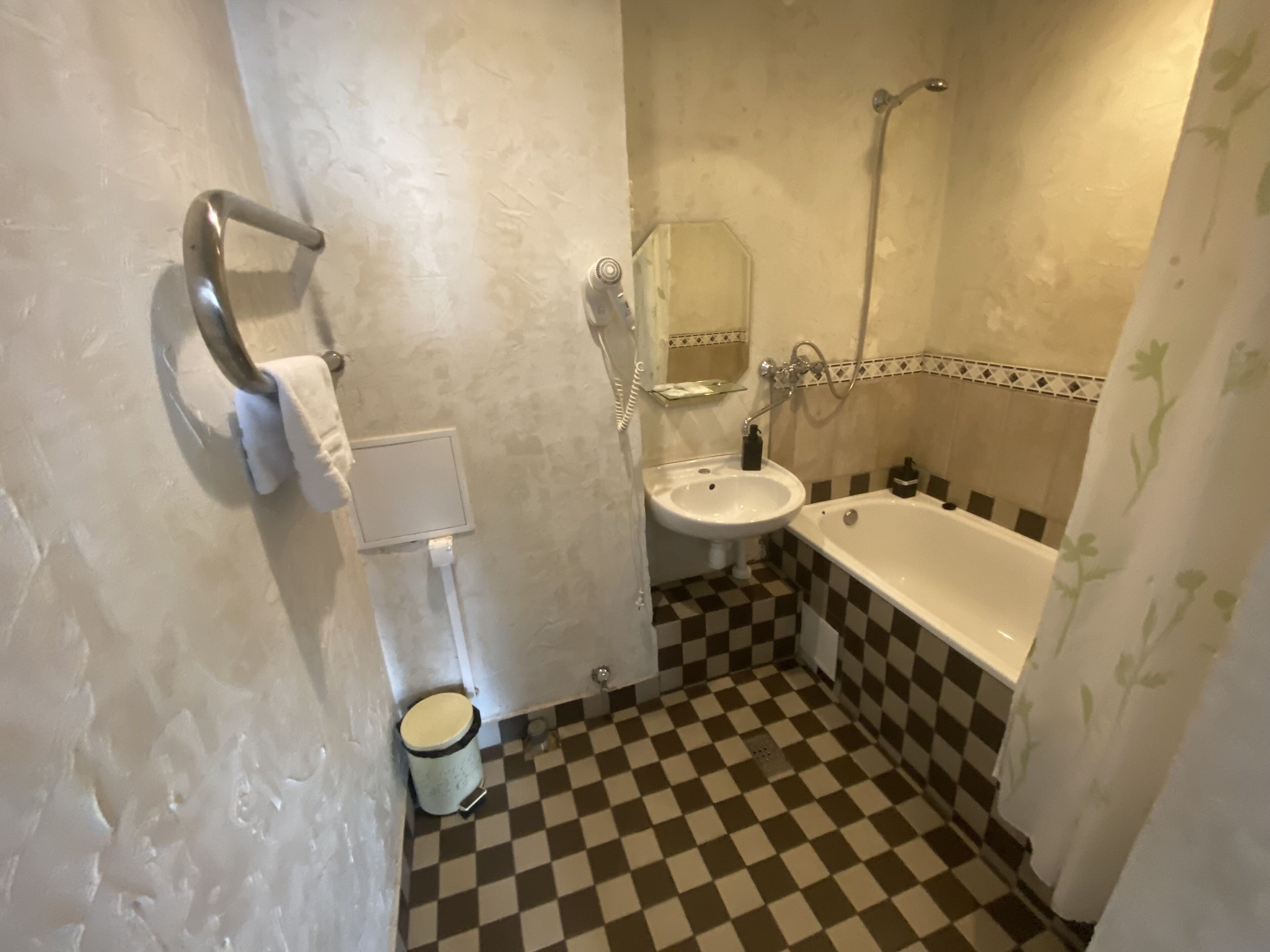 A bathroom with a checkered floor, a sink, a bathtub, and a toilet.