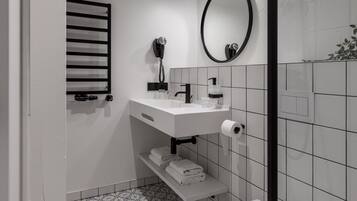 A modern bathroom with a white sink, mirror, and toilet.