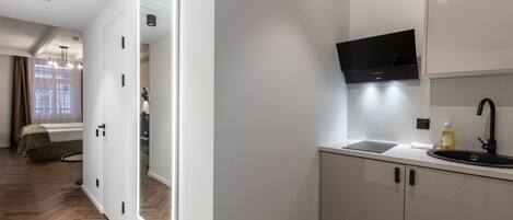 A modern kitchen with white cabinets, a black countertop, and a built-in TV.