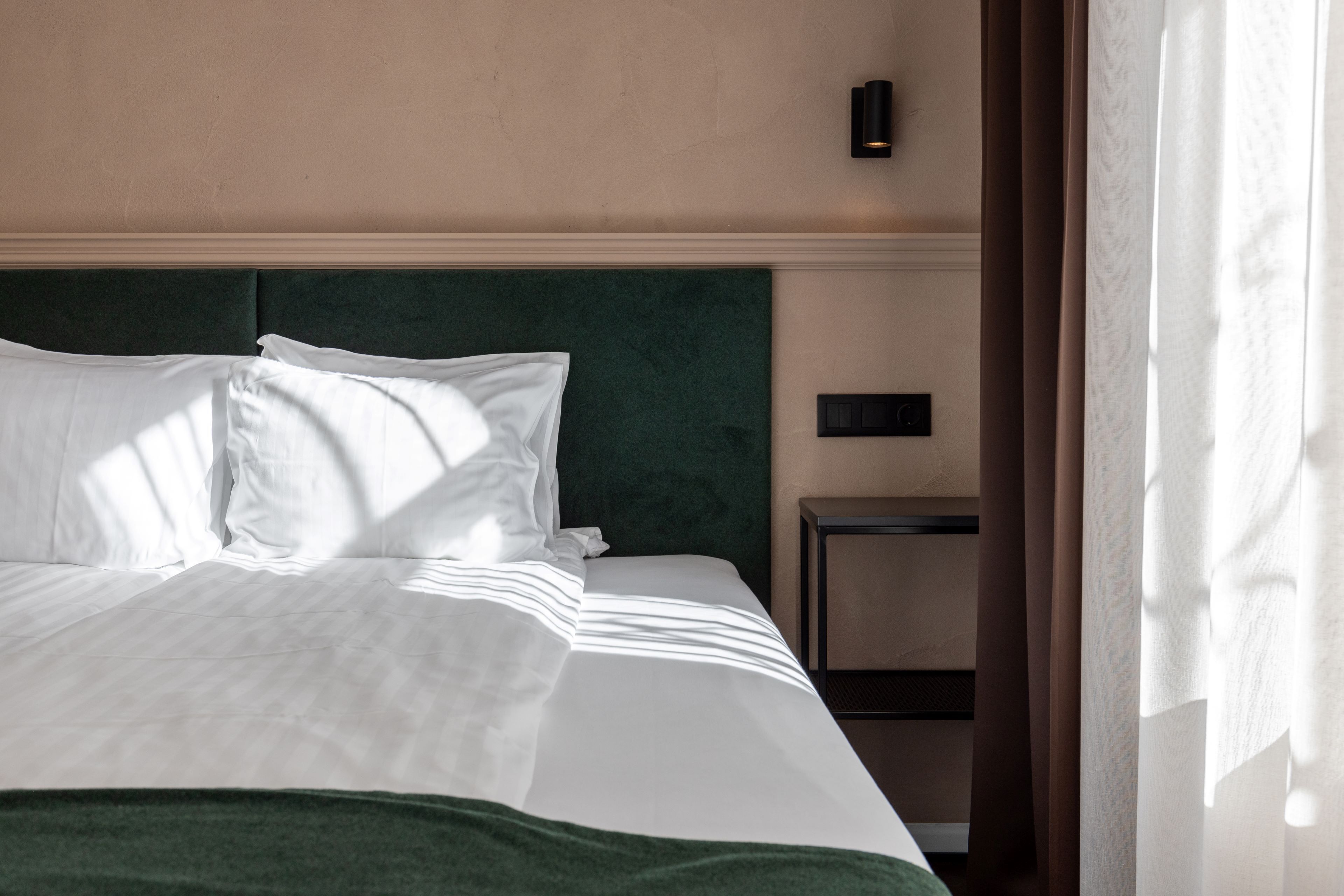 Un letto rifatto con lenzuola bianche e una testiera verde.