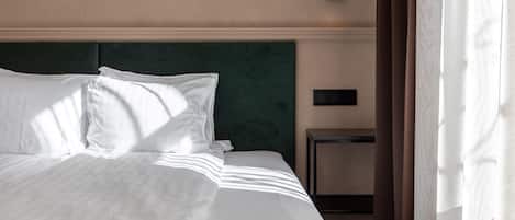 A neatly made bed with white linens and a green headboard.