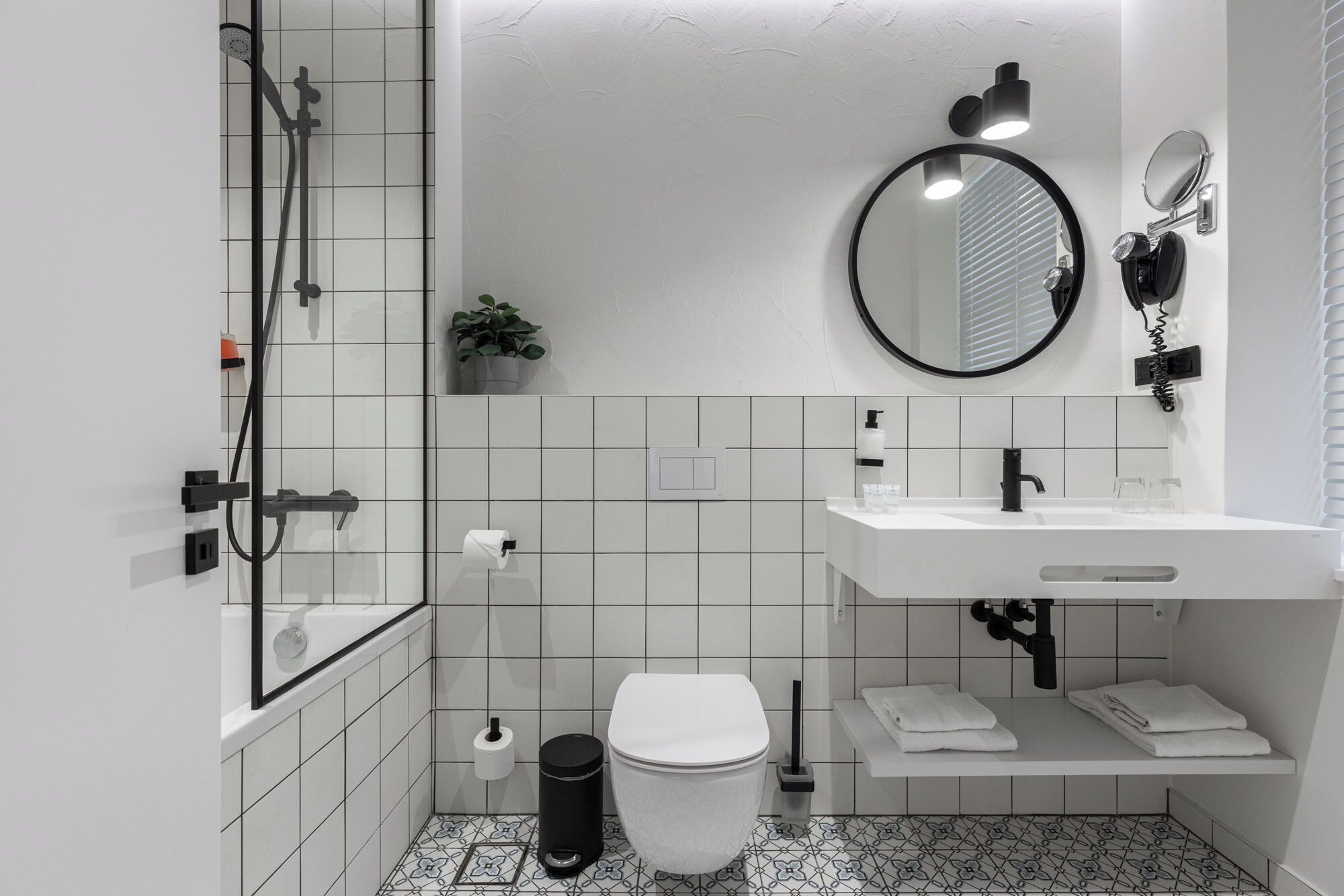 A modern bathroom with a shower, toilet, sink, and a mirror.