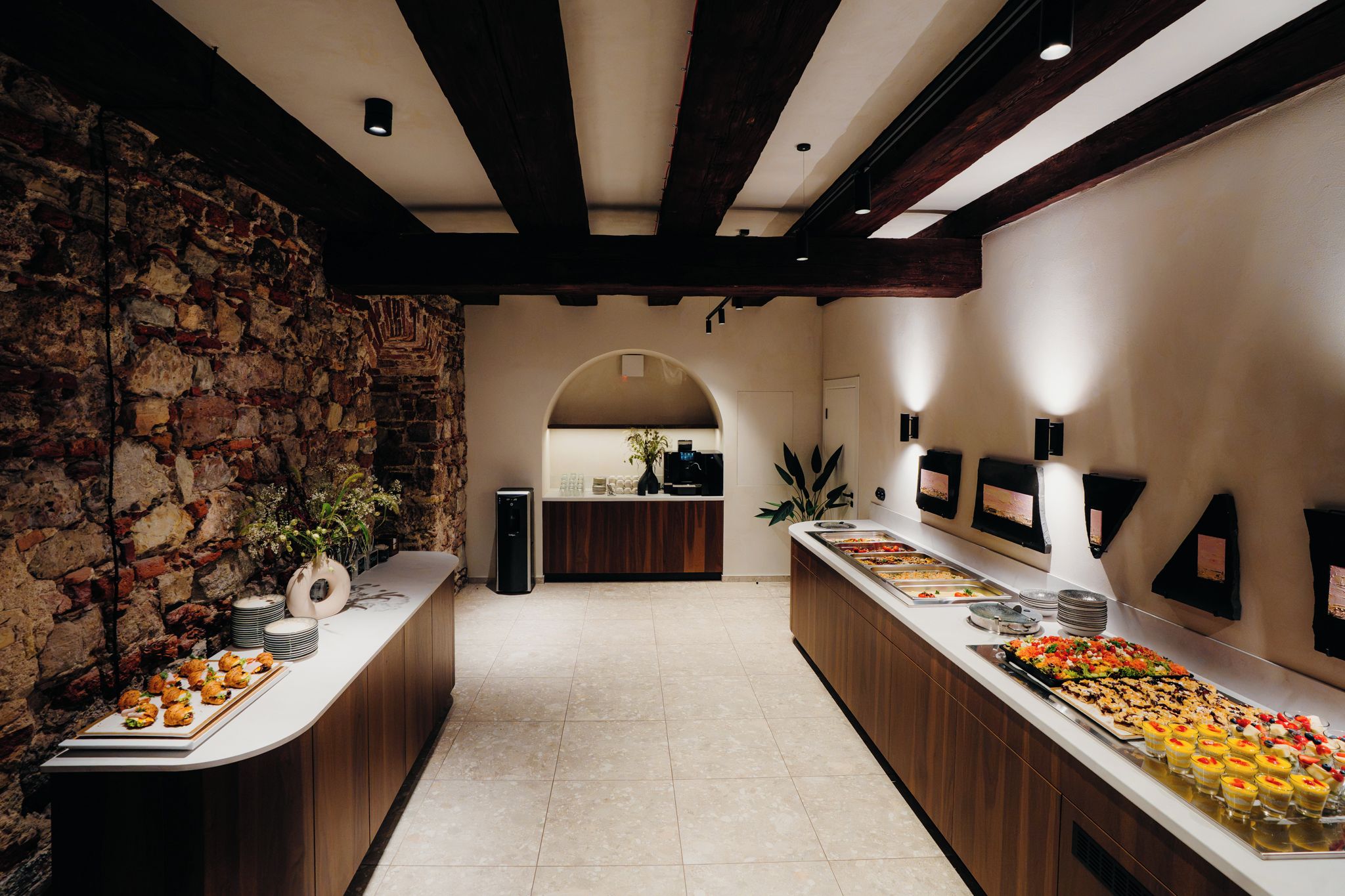 Zona de buffet con pared de piedra, vigas de madera y suelo de baldosas.