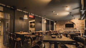 A restaurant with wooden tables and chairs, a brick wall, and a modern ceiling design.