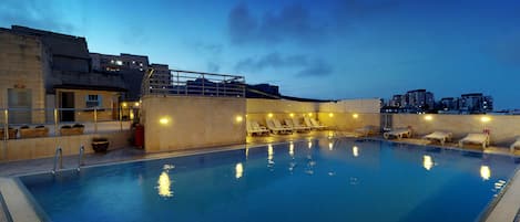 Una piscina al aire libre de temporada, sombrillas