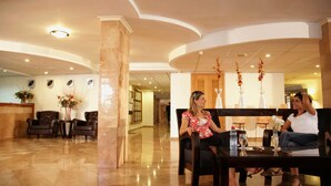Un vestíbul amb sòl de marbre, una recepció i dos sofàs.