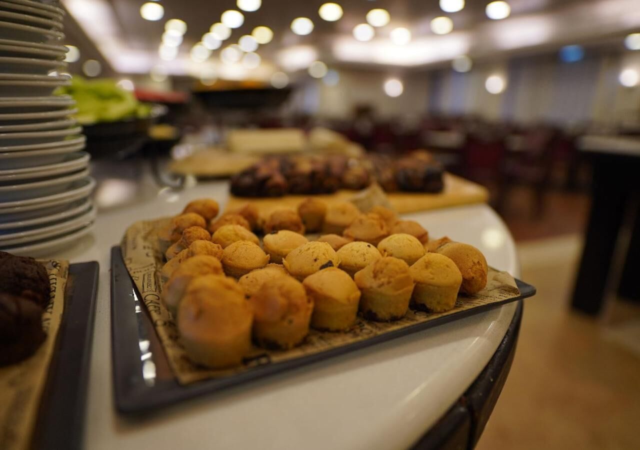 Una mesa de buffet con diversos alimentos, entre ellos pasteles y postres.