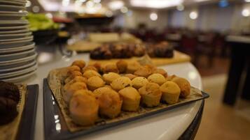 Una mesa de buffet con diversos alimentos, entre ellos pasteles y postres.