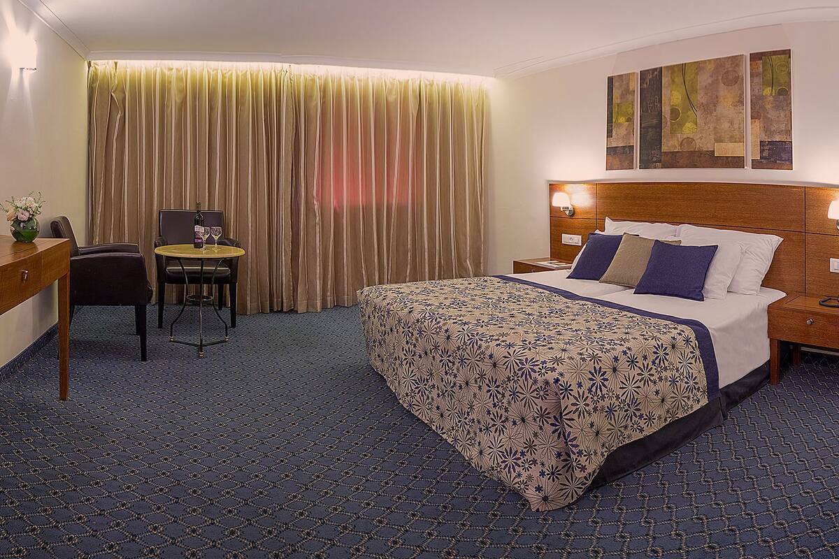 A hotel room with a bed, a desk, a chair, a television, and a curtain.