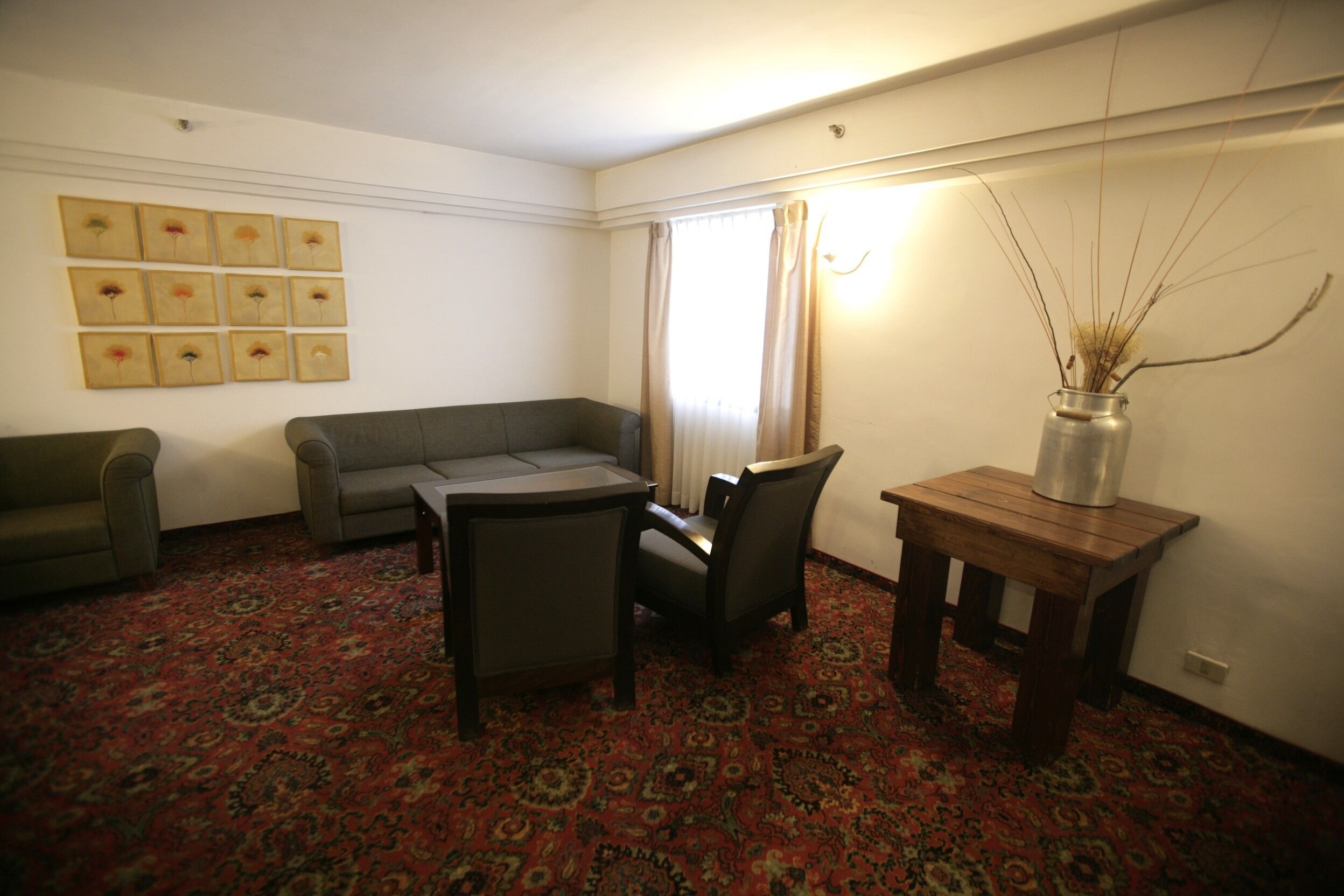 A living room with a patterned carpet, a sofa, a coffee table, and a vase with branches.