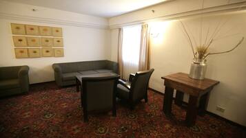 A living room with a patterned carpet, a sofa, a coffee table, and a vase with branches.