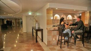 Un vestíbul d'hotel amb un terra negre i blanc a quadradets, una taquilla d'admissió i una zona de bar.