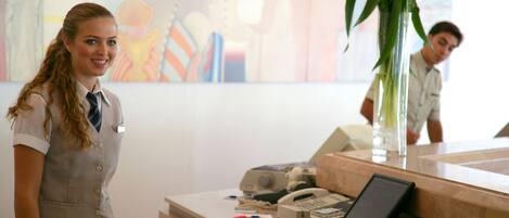 A reception area with a receptionist, a phone, a vase with flowers, and a large abstract painting on the wall.