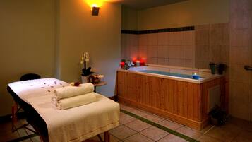 Relax in a serene spa room with a bathtub, massage table, and candles.