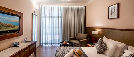 Quarto de hotel com cama, televisão, escrivaninha e cadeira.