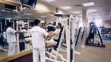 A gym with exercise equipment, a large mirror, and a clock on the wall.