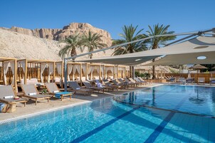 Una piscina techada, una piscina al aire libre, sombrillas