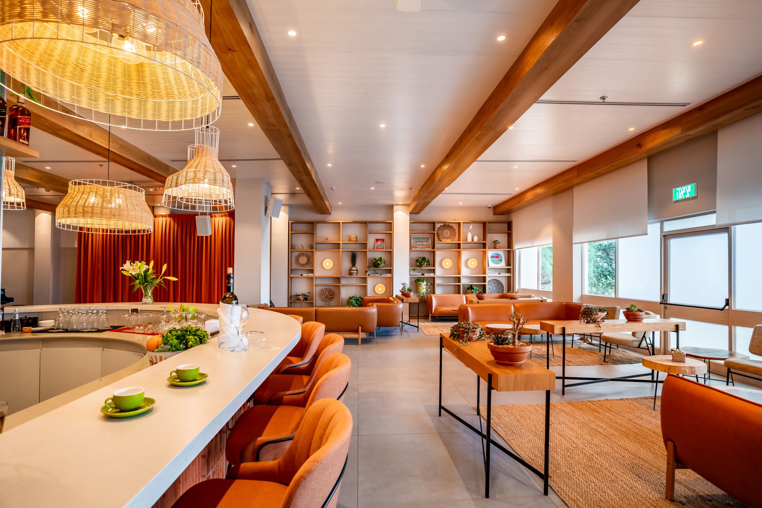 A modern hotel lobby with a central bar area, seating arrangements, and a view of the outdoors through large windows.