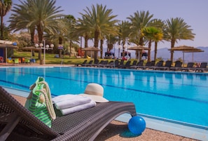 Una piscina al aire libre, sombrillas, sillones reclinables de piscina