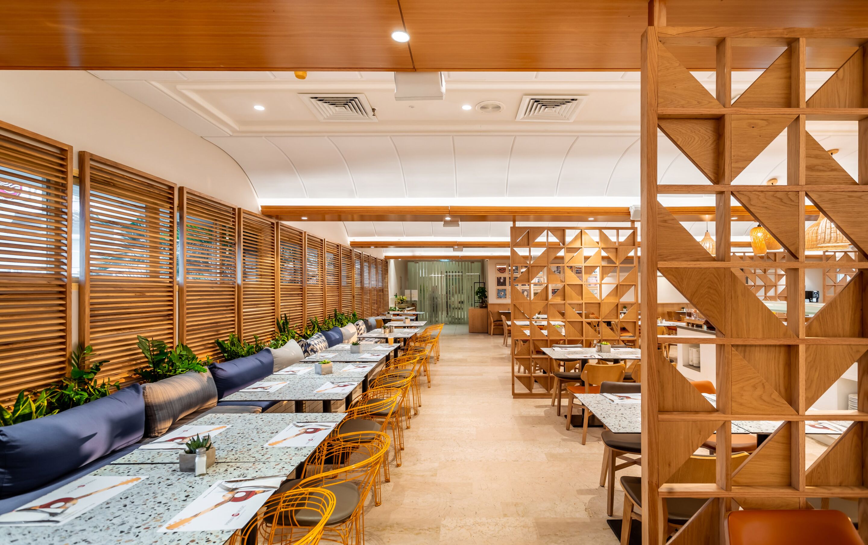 Un restaurante moderno con separadores de madera, mesas largas y asientos cómodos.