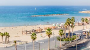 Una playa con palmeras, sombrillas y un muelle.