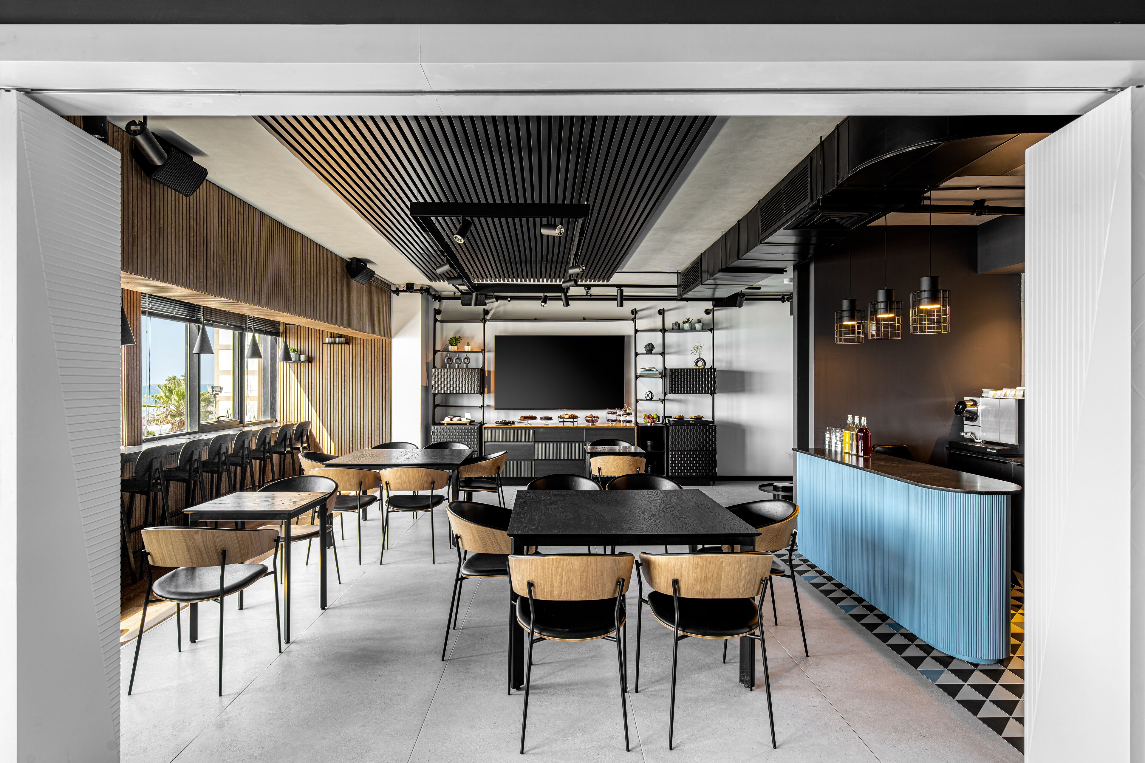 A modern restaurant with a central dining area, a bar, and a kitchen in the background.