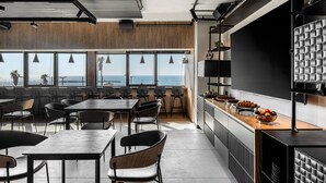 Una cocina moderna con una isla grande, paneles de madera y vista al mar.