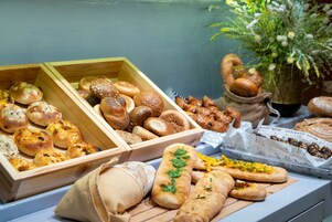 Variedad de panes y pasteles expuestos en cajas de madera y una tabla de madera.