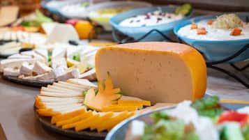 A buffet with various dishes including cheese, salads, and other food items.