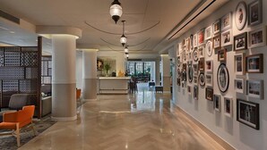 A spacious lobby with a polished marble floor, a reception desk, and a wall adorned with framed photographs. - Prima Kings Hotel (Jerusalem)