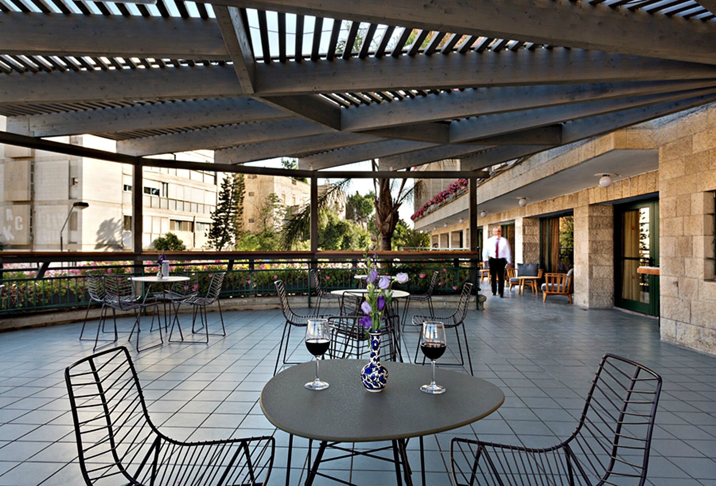 Un patio al aire libre con mesas y sillas, un jarrón decorativo y copas de vino.