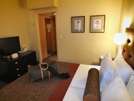 Una habitación de hotel con una cama, televisión, escritorio y una silla.