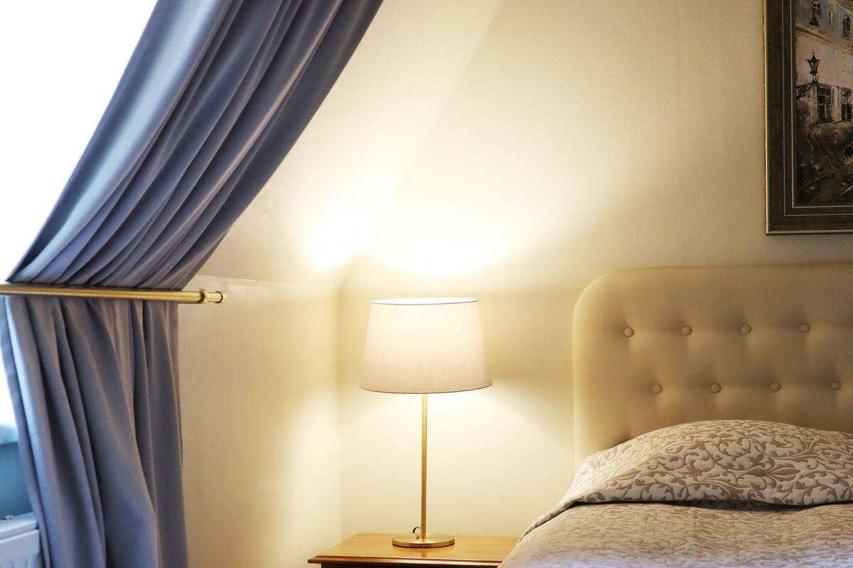 A hotel room with a bed, a nightstand with a lamp, and a framed picture on the wall.