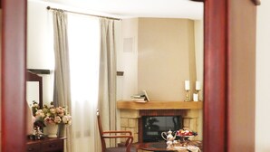 Una habitación de hotel con cama, escritorio con silla, chimenea y televisión.