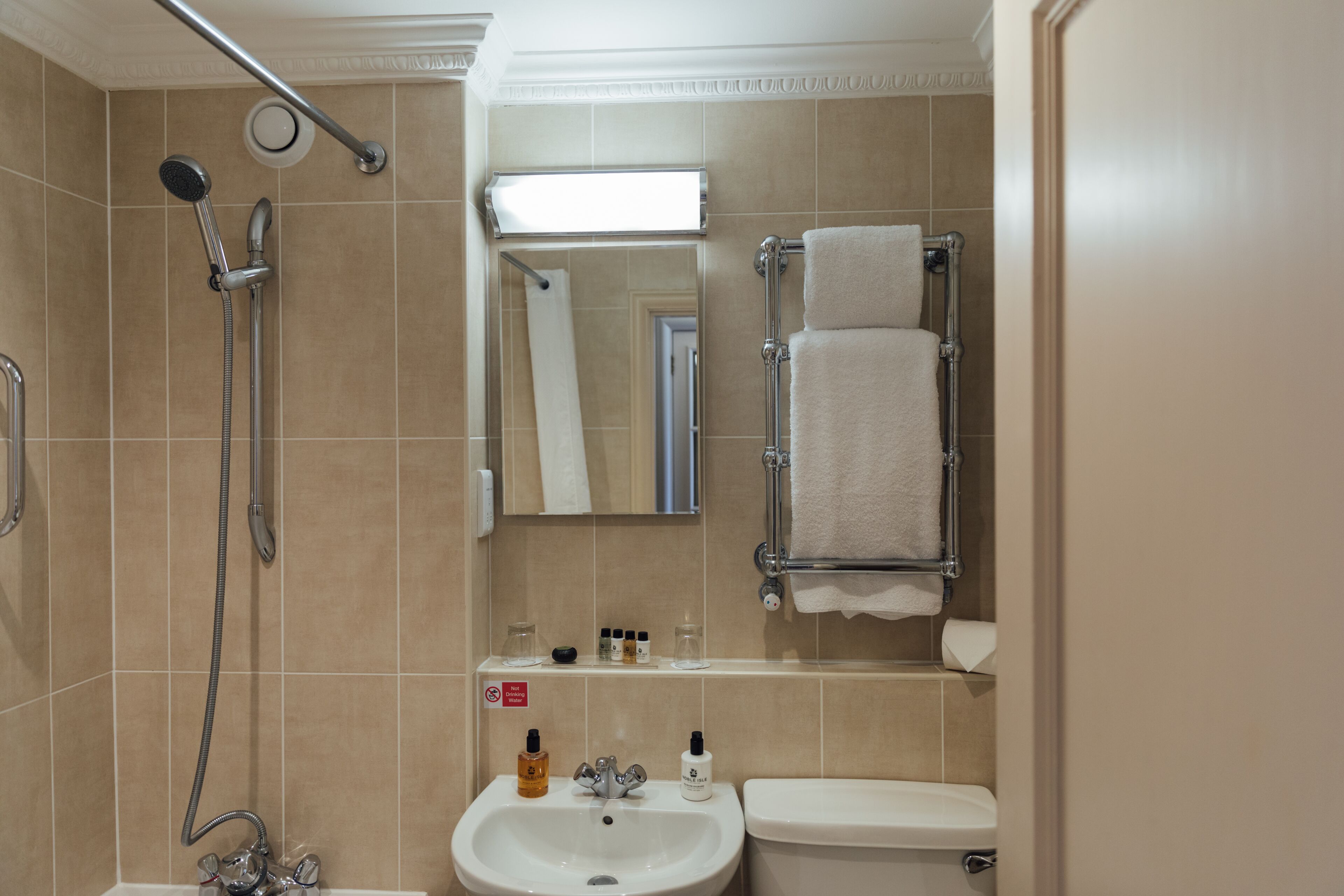 A bathroom with a shower, sink, toilet, and towel rack.