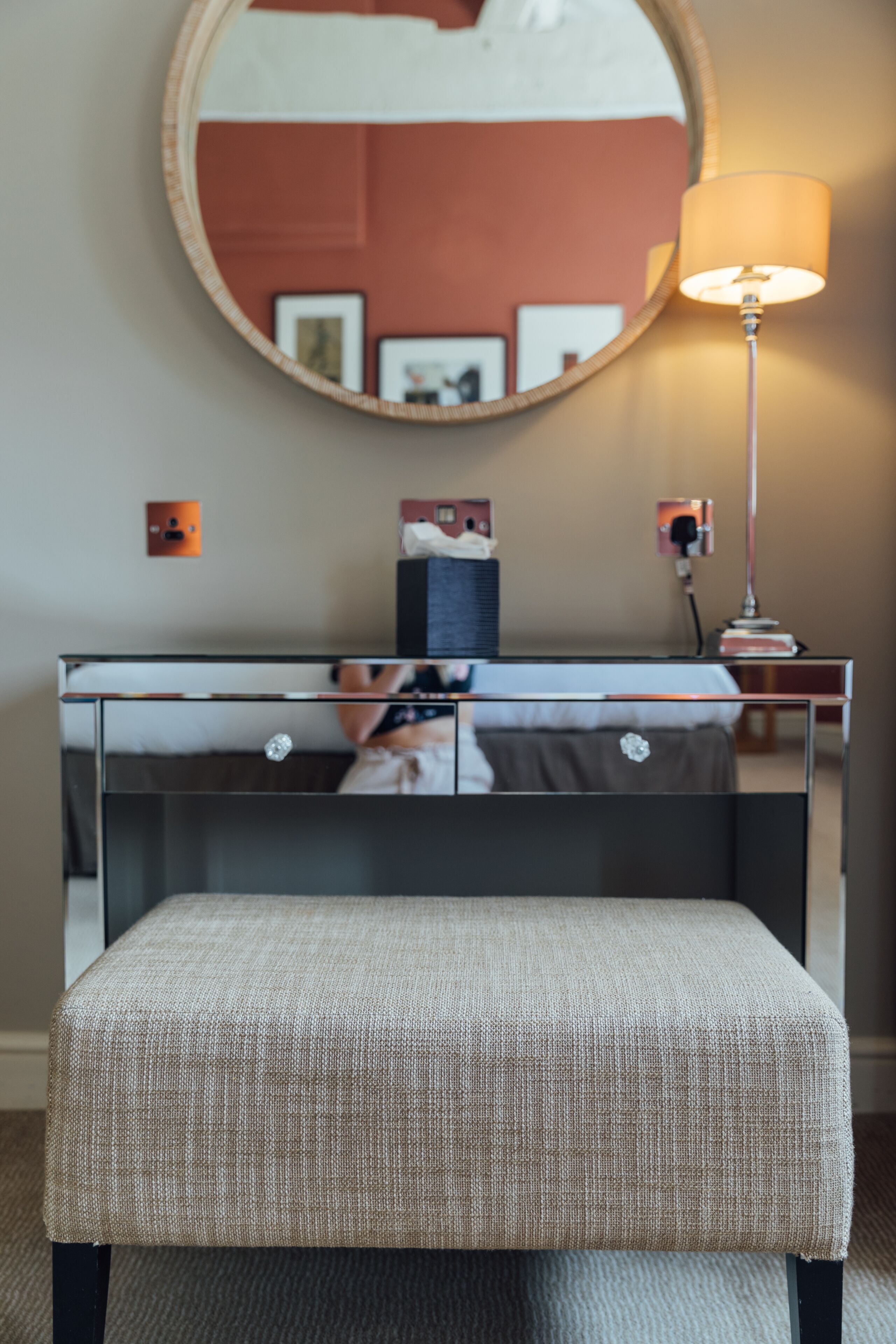 Una habitación con una cama, una mesita de noche, una lámpara y un espejo en la pared.