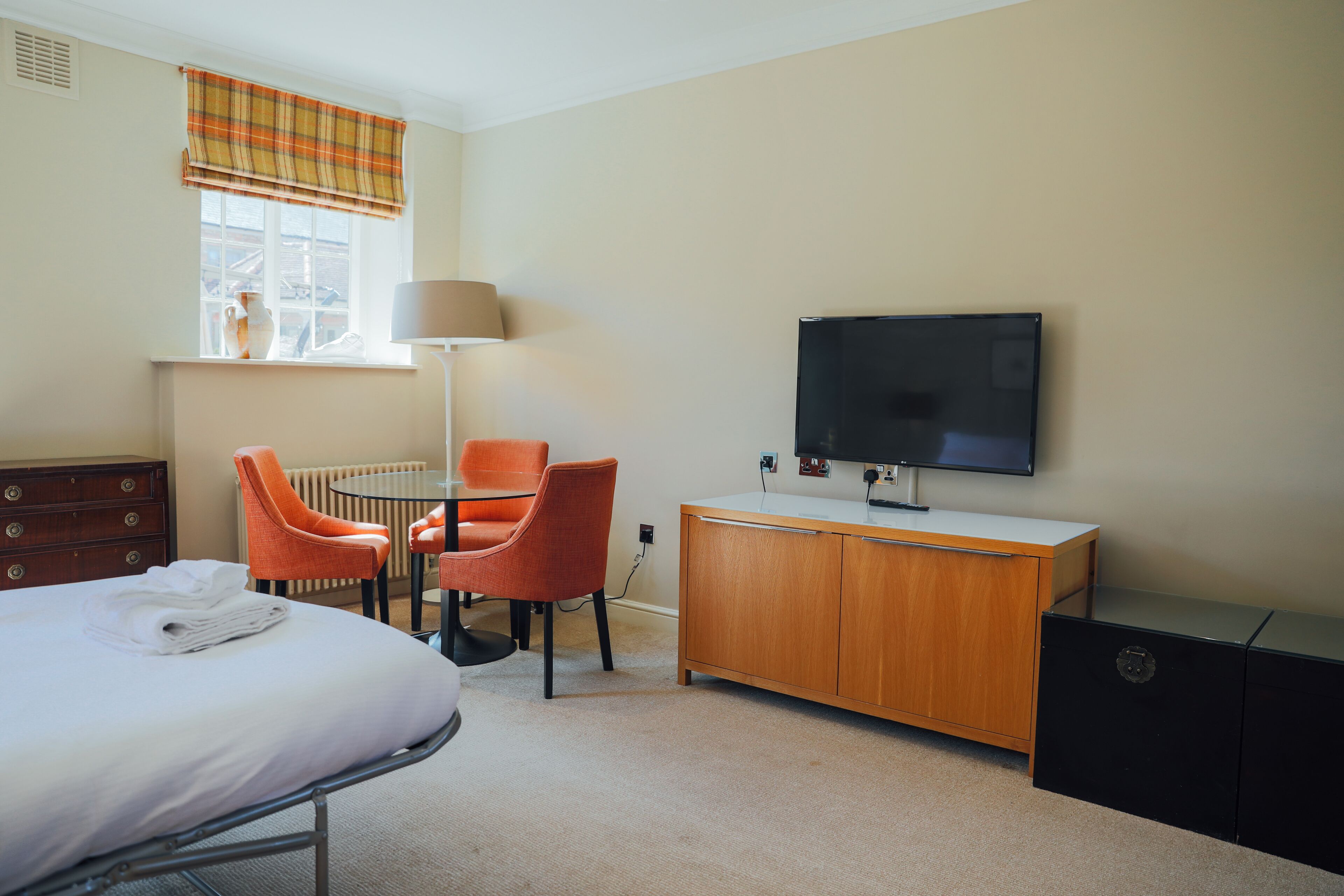 A hotel room with a bed, a desk, a chair, a television, and a cabinet.