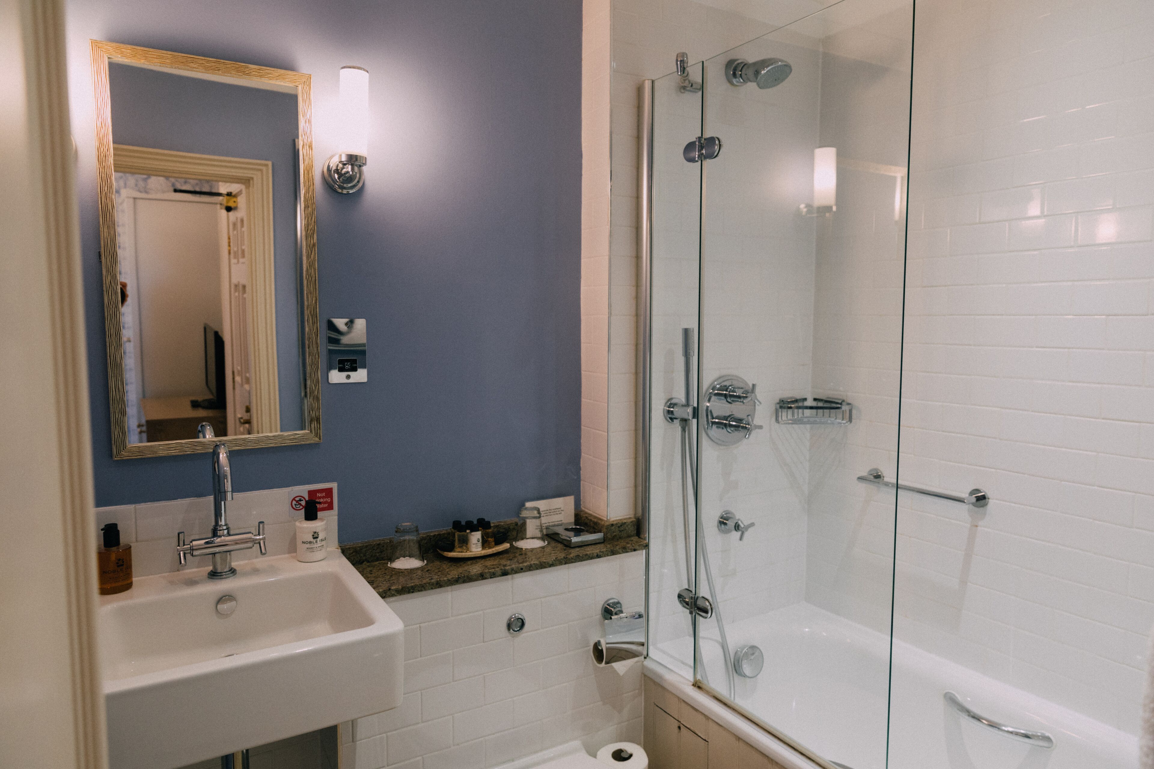 A modern bathroom with a sink, mirror, and glass-enclosed shower.
