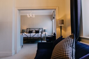 Una habitación de hotel con cama, escritorio, silla, lámpara y candelabro.