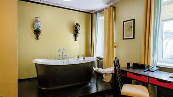 Un baño con una bañera independiente, un escritorio con teléfono y una silla.