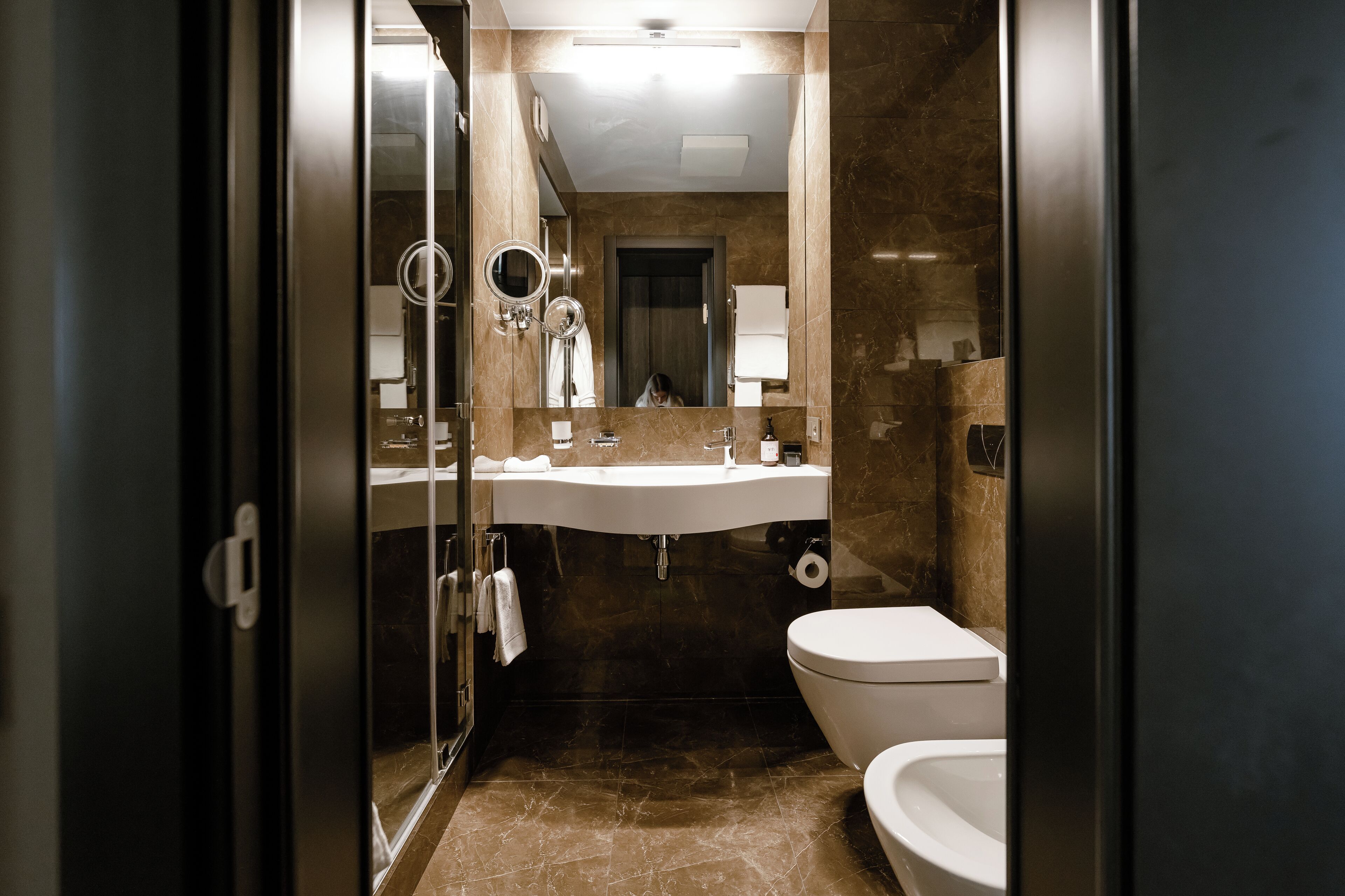 A modern bathroom with a glass shower enclosure, a white sink, and a toilet.