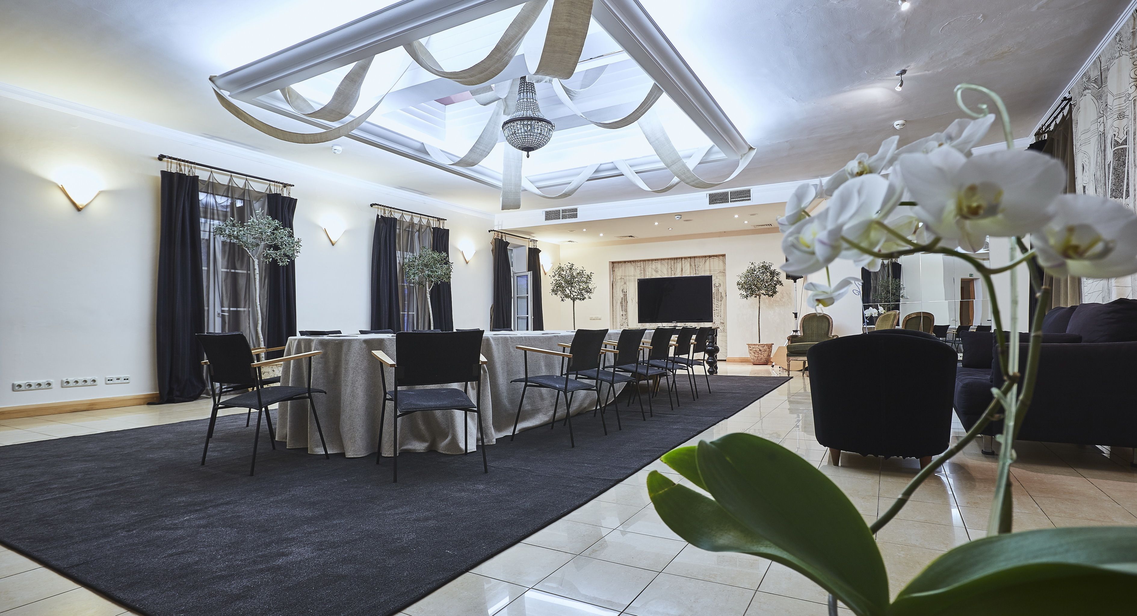 A modern living room with a dining area, a fireplace, and a large window with curtains.