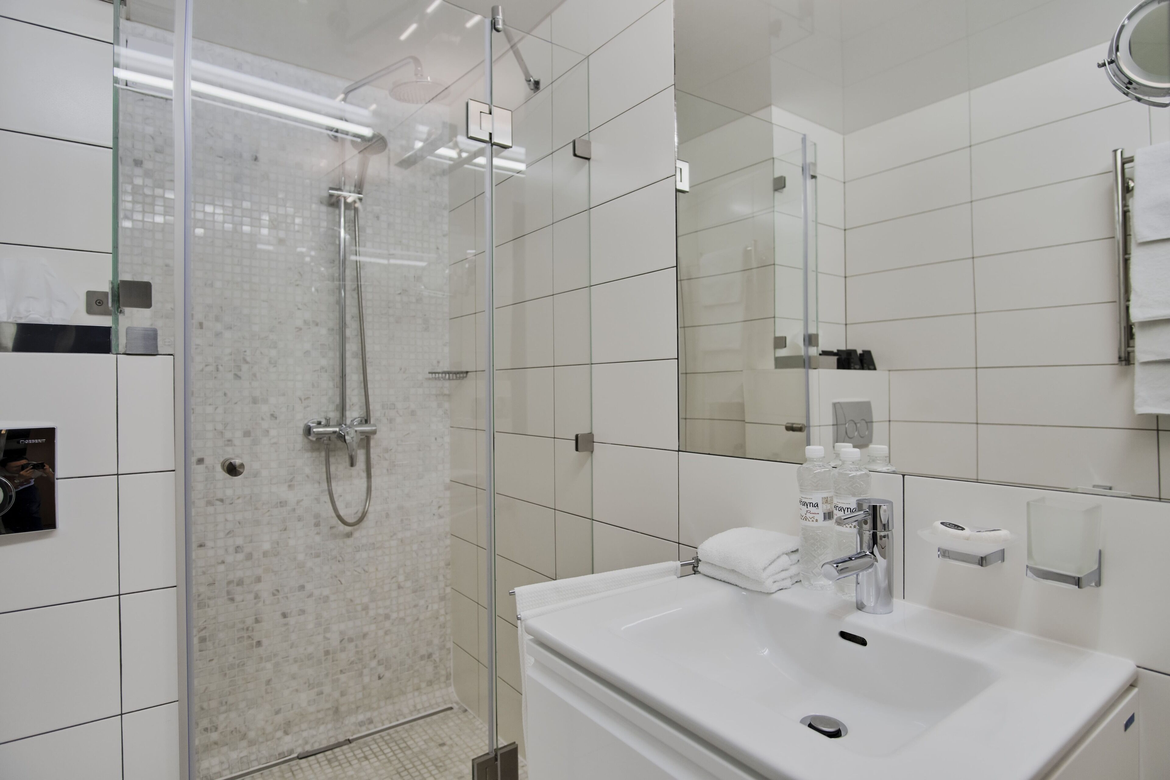 A modern bathroom with a glass-enclosed shower, a white sink, and a mirror.