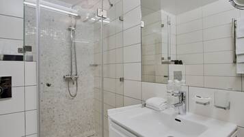A modern bathroom with a glass-enclosed shower, a white sink, and a mirror.