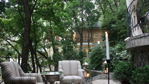 An outdoor seating area with two striped armchairs, a small table, and a lantern. - Boutique Hotel Vozdvyzhensky (Kyiv)