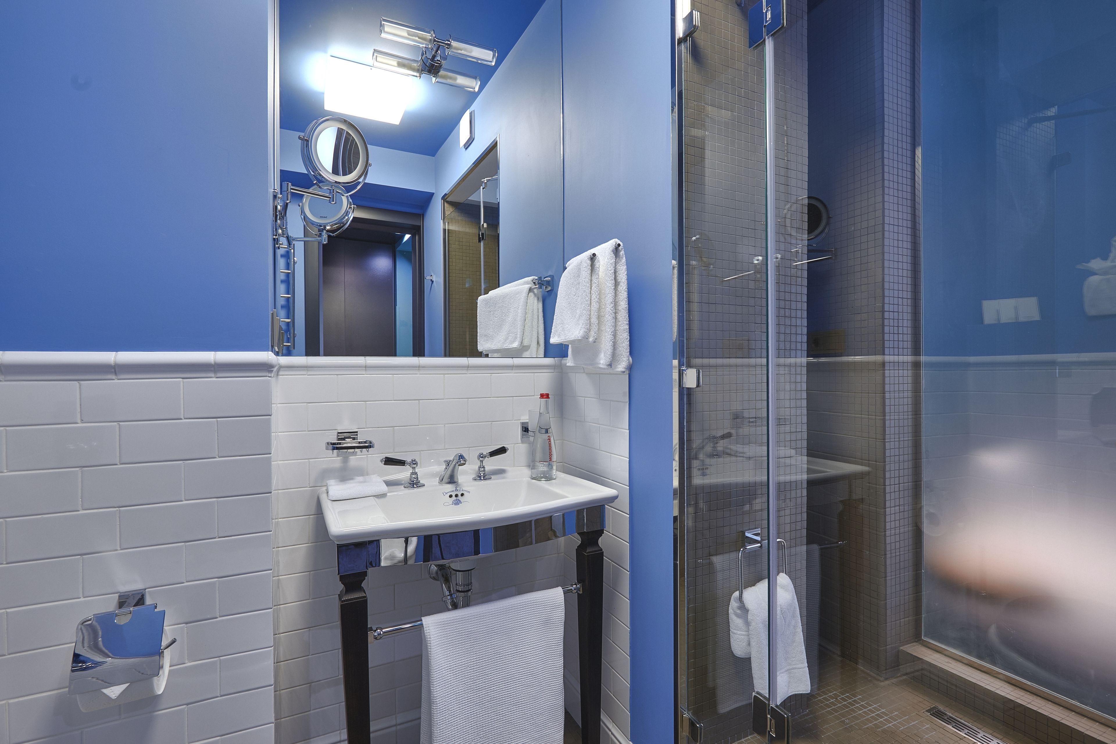 A bathroom with a white sink, mirror, and glass shower enclosure.