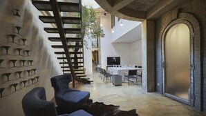 A modern interior with a staircase, seating area, dining space, and a large arched doorway. - Boutique Hotel Vozdvyzhensky (Kyiv)