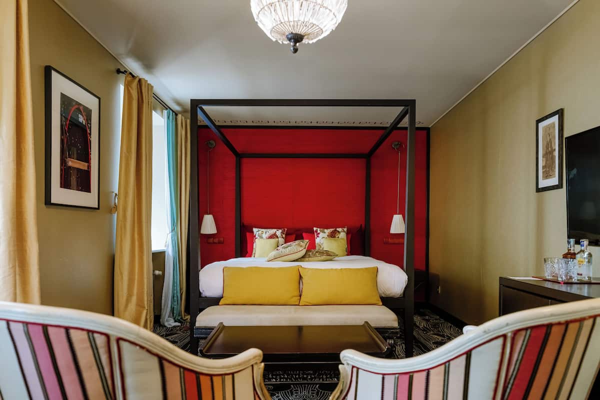 Ett hotellrum med en säng med himmelssäng, en platt-TV och ett skrivbord med en stol.